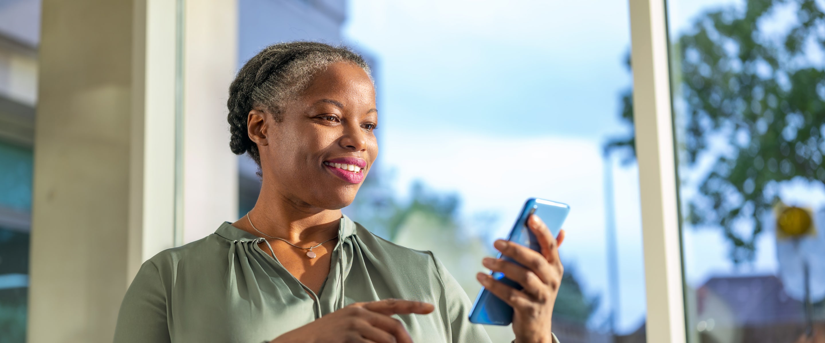 A middle-aged woman is looking down at her smartphone.