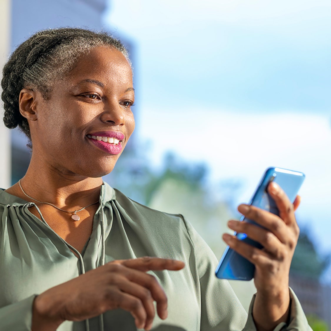 A middle-aged woman is looking down at her smartphone.