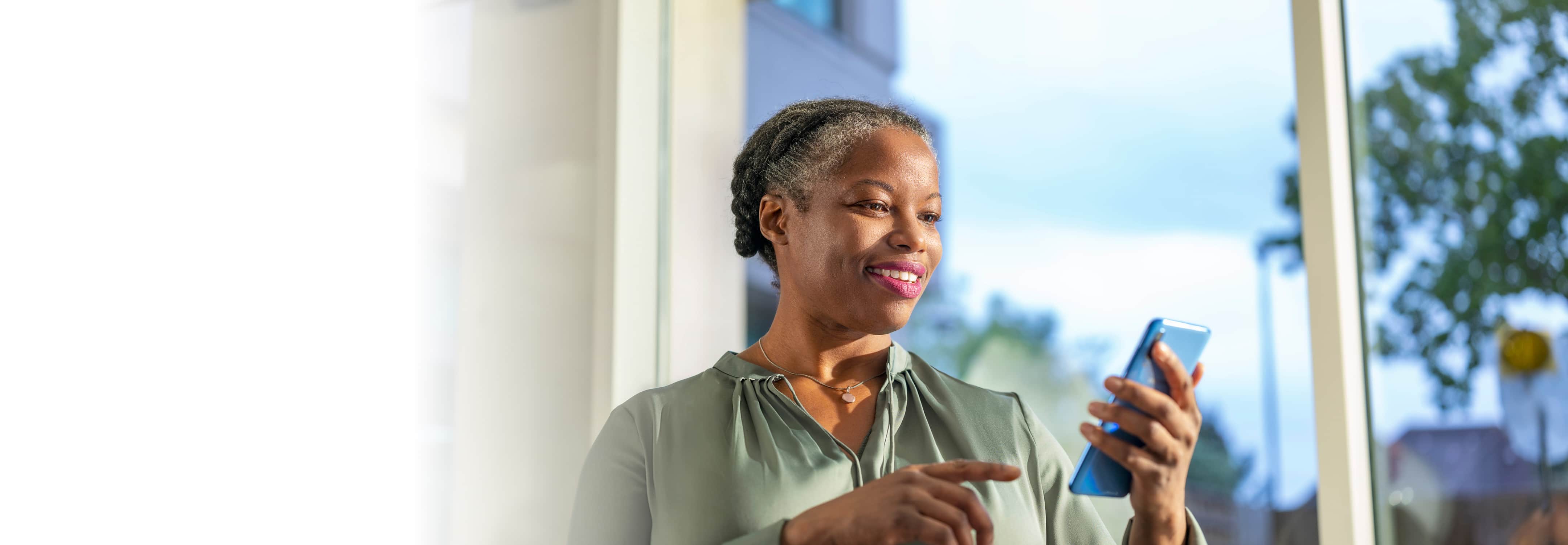 A middle-aged woman is looking down at her smartphone.