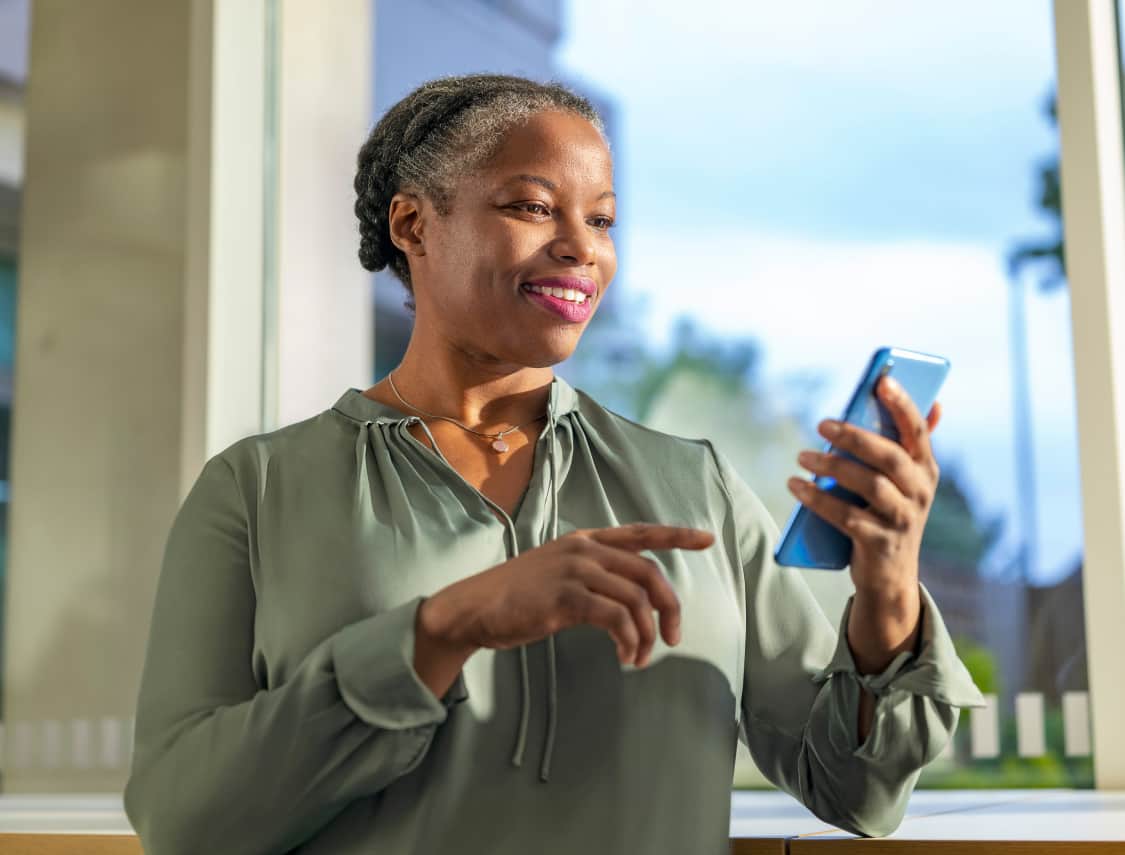 A middle-aged woman is looking down at her smartphone.