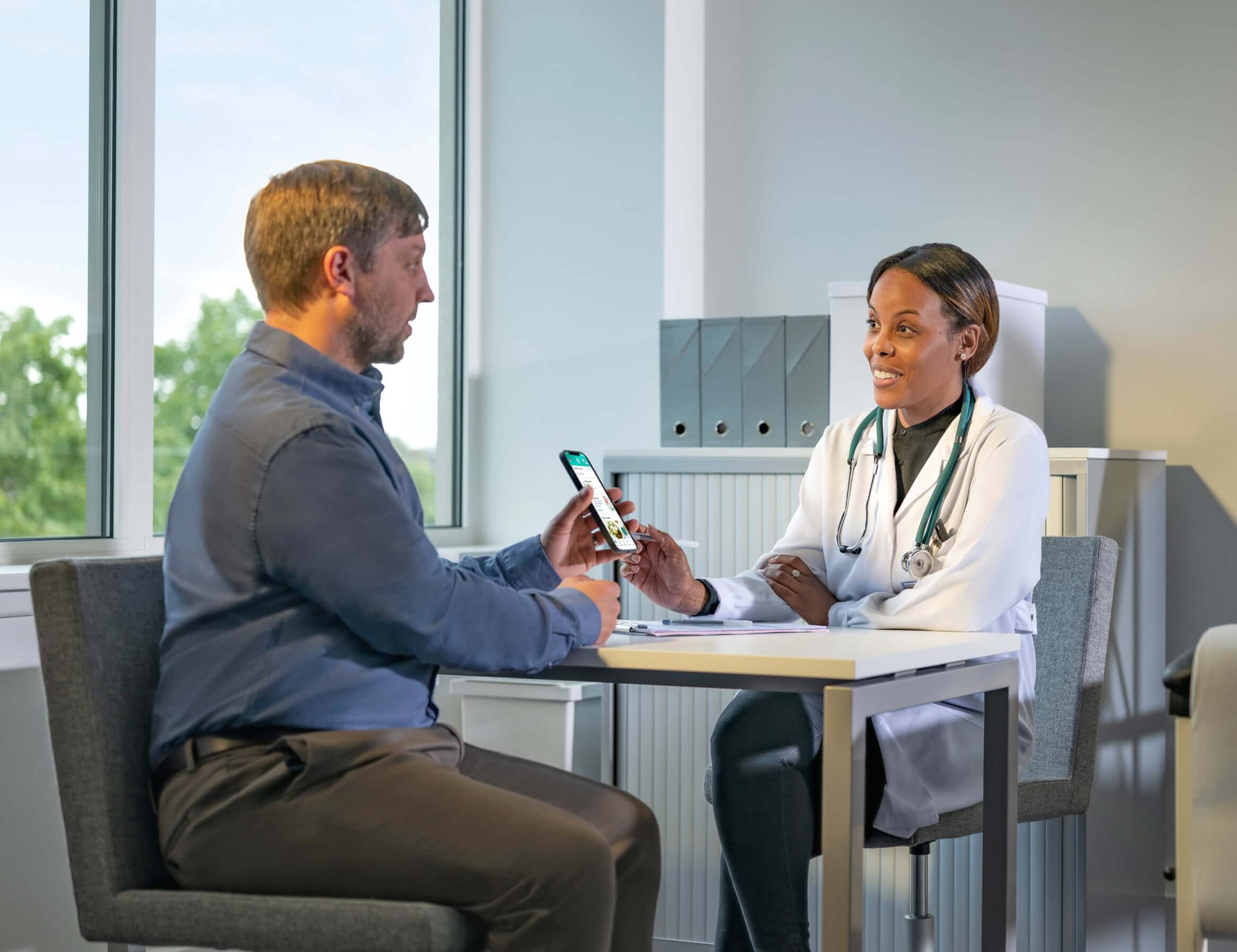 Doctor studying results with patient on his smart phone